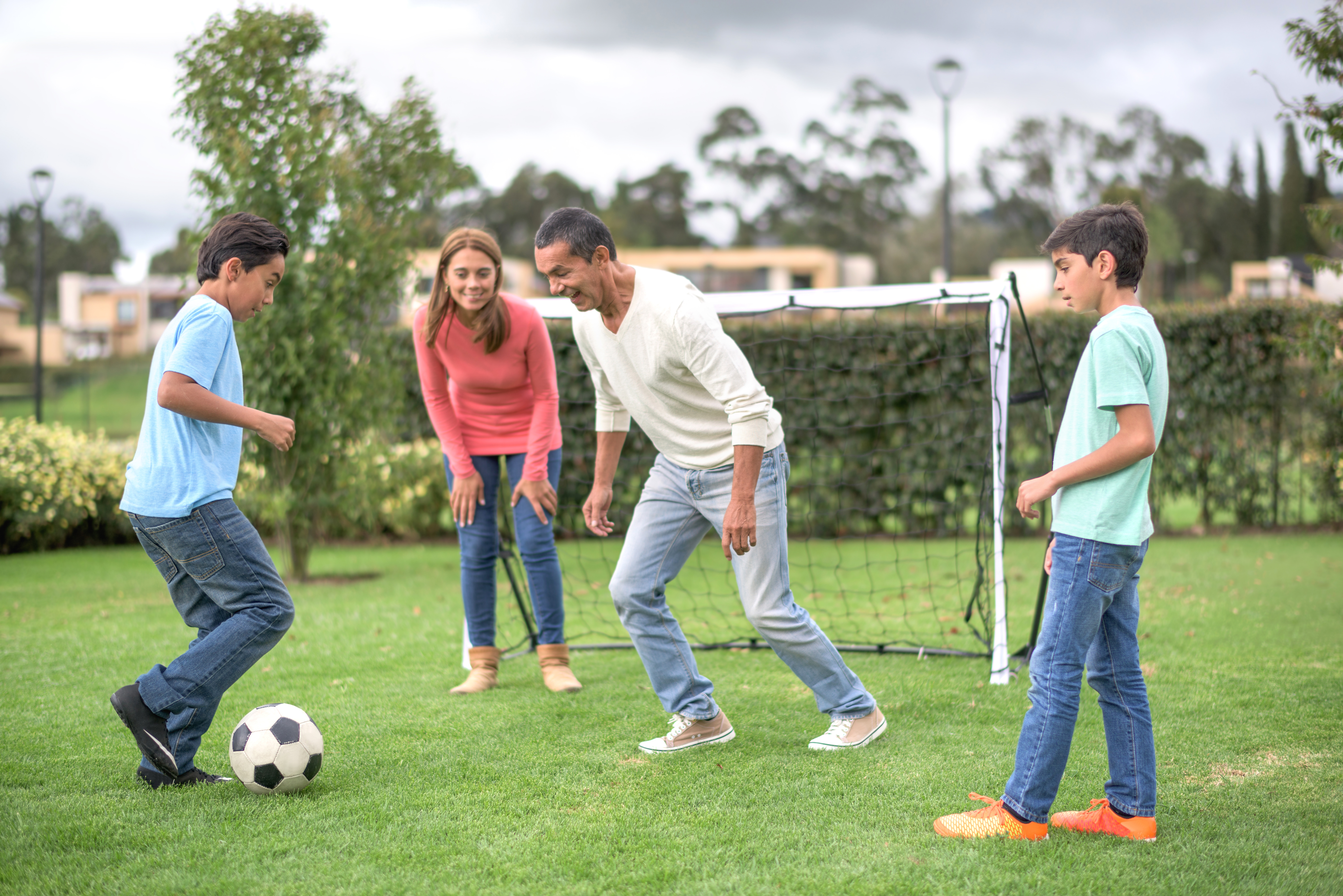 Dad playing soccer with kids at the park